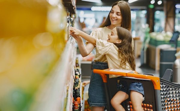 Family at the supermarket. Woman in a brown t-shirt. People choose products. Mother with daughter.