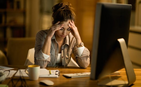Young woman having a headache after working on a computer at night at home.